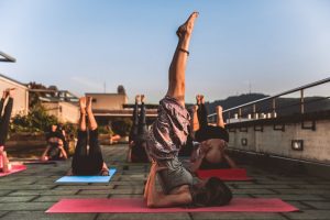 People practicing yoga on mats outdoors during sunset, focusing on wellness.